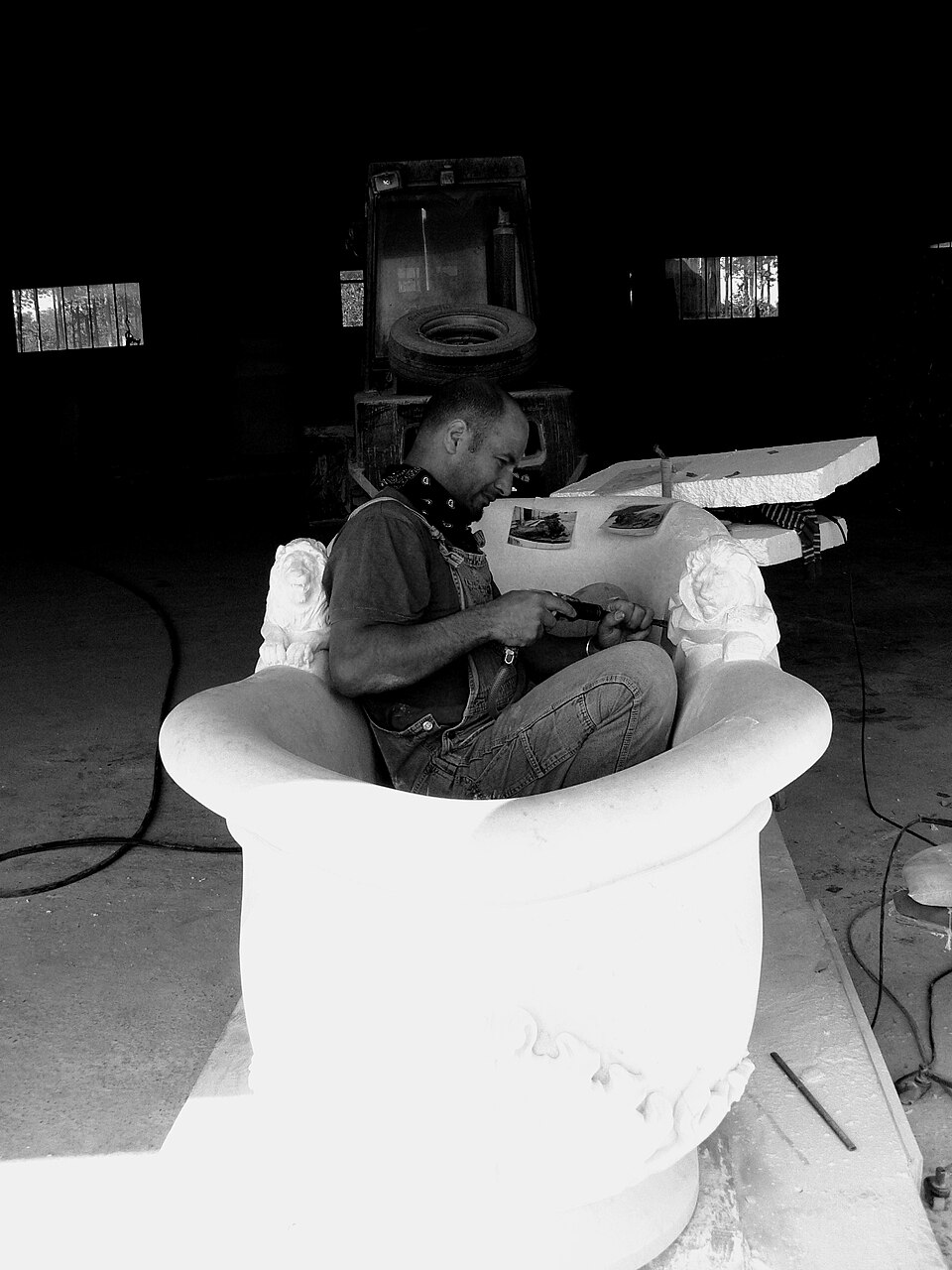 Artisan hand-carving the interior of a marble bathtub inside the workshop