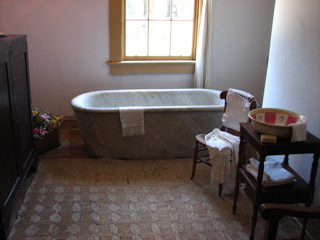 Solid white marble bathtub carved from a single block, in a light-filled room